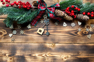 House key with keychain cottage on a festive eco friendly, natural background with Christmas tree....