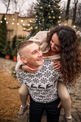A woman and a man are standing near the Christmas tree, they are happy, new year's mood