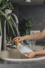 Close-up of child's hands washing dishes with eco dish brush.
