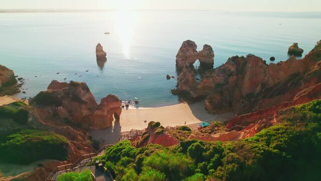Aerial view of Praia do Camilo by rocky coastline in Lagos, Algarve, Portugal. Scenic view of Praia do Camilo from above - a tourist crowded and famous relaxing holiday beach in 4K.