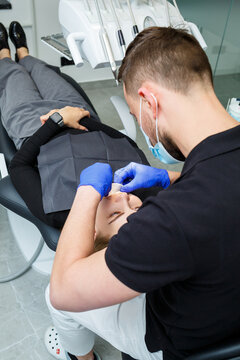 The orthodontist puts metal braces on the patient's teeth. Orthodontic dental treatment. High quality photo