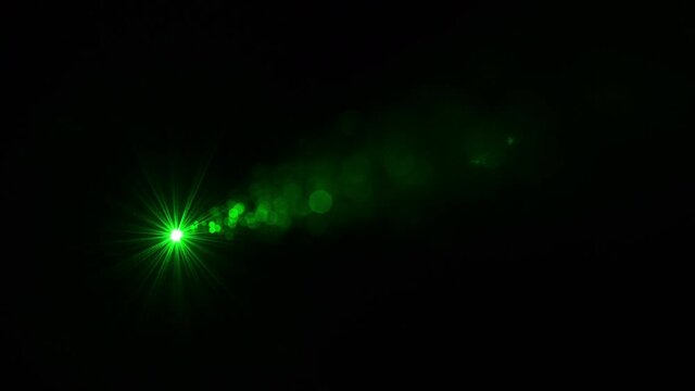 The green laser ray shining in darkness. slow motion
