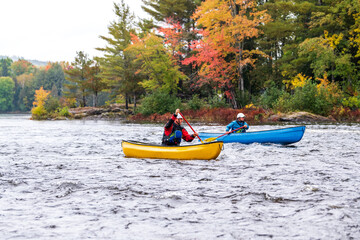 A solo canoeist practices strokes on a rainy fall day during  a “moving water” paddling course. Shot at Palmer Rapids on the Madawaska River an iconic paddling destination in Eastern Ontario, Canada