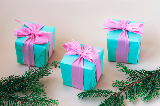 Three teal blue present boxes with bows and fir branches. Winter holidays concept. Selective focus
