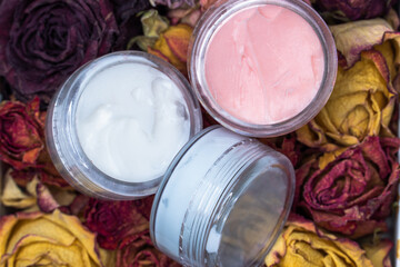 Face cosmetics. Facial creams of different colours on a flower background