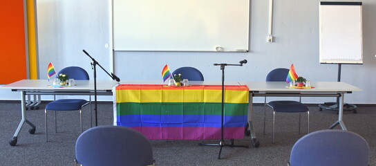 Podium mit Regenbogenfahne und Mikrofonen