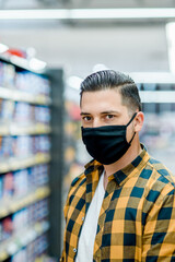 Fototapeta na wymiar Young handsome man in a supermarket wearing protective mask while grocery shopping