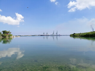 calm sea with industrial crane towers in the horizon 