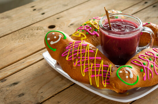 Traditional composition of guaguas de pan with colada morada, a typical ecuadorian dish for the day of the dead. Rustic wooden table. Latin america gastronomy and culture concept.