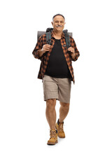 Full length portrait of a cheerful mature hiker carrying a backpack and walking towards camera