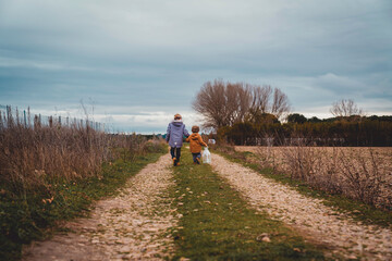 General shot of two boys with their backs turned walking down a country road.