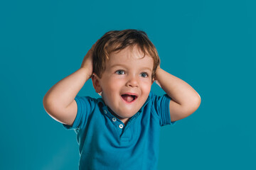 Close-up of a little boy putting his hands on his head in surprise
