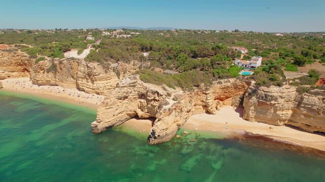 Aerial view of Marinha Beach or Praia da Marinha, Algarve coast, Portugal in 4K. A crowd of people from above relax and get tan under the sun at one of the most famous beaches in Portugal.
