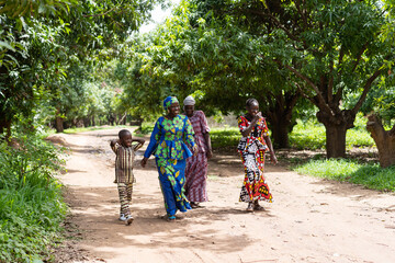 A group of happy black African villagers strolling on a dirt road in a West African neighborhood © Riccardo Niels Mayer
