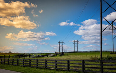 Electric power lines and polls passing through horse farms in rural Kentucky