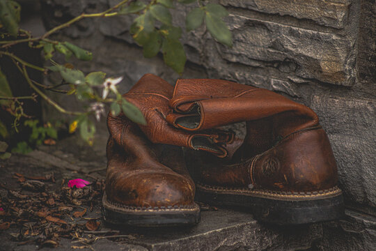 worn Work boots, cowboy boot placed on stone wall in park