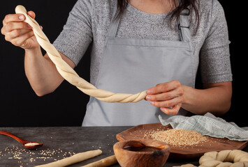 delicious Turkish bagel with sesame seeds known as susamli simit.  A woman is making twisted rolls...