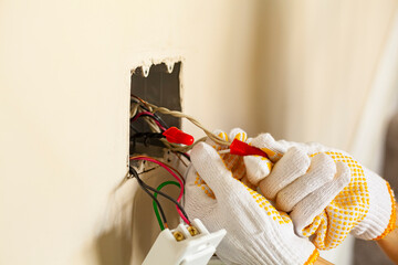 An electrician is replacing a wall switch. A DIY project concept. High voltage danger. The...
