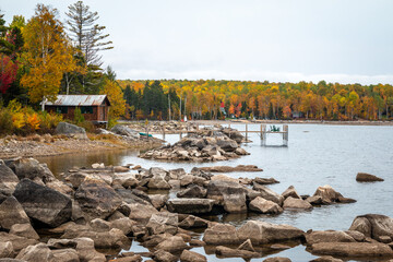 A rocky shoreline with a cabin. A wonderful scene during fall.  - 463937194