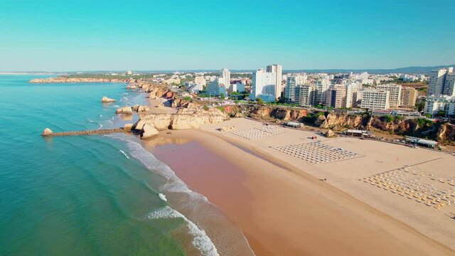 Drone 4K aerial view of Praia da Rocha Beach in Portim&atilde;o, Algarve, Portugal. Famous luxury holiday hotels and expensive residential areas in Portugal, a coastline with turquoise water and a huge beach