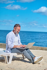 Man working on laptop on seashore