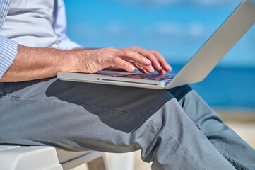 Male hands working on laptop outdoors