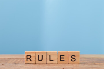 Wooden square letters with text RULES on wooden table.