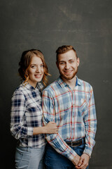 Obraz na płótnie Canvas young couple in plaid shirts hugs on gray background