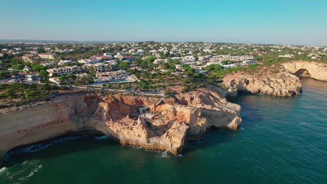Aerial view of Carvoeiro Boardwalk with luxury stunning hotels and buildings. Coastal Carvoeiro town in Lagoa, Algarve, Portugal, Europe by the Ocean with people relaxing on holiday having a good time
