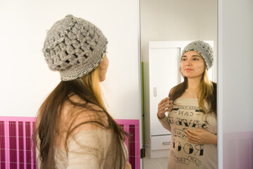 joven mujer morena feliz frente al espejo probando o eligiendo ropa de abrigo con foco selectivo....