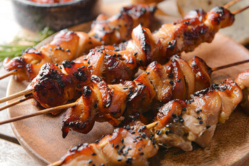 Plate with grilled chicken skewers on wooden background
