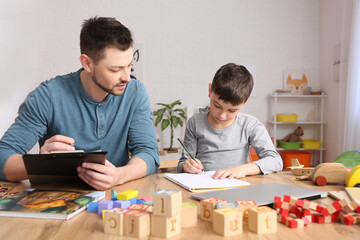 Male psychologist working with little boy in office. Autism concept