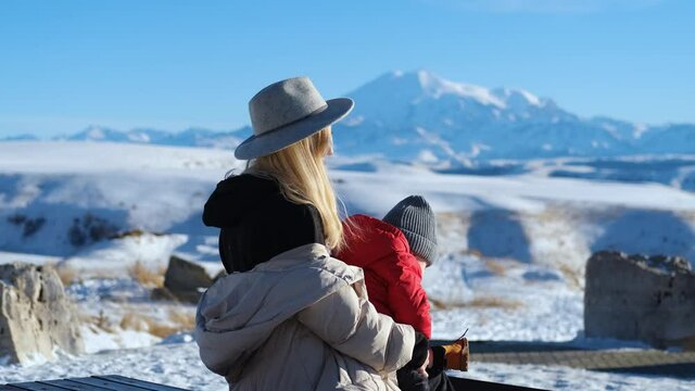 stylish mom with little son on the background of snowy mountains