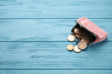 Pink wallet with coins on blue wooden background