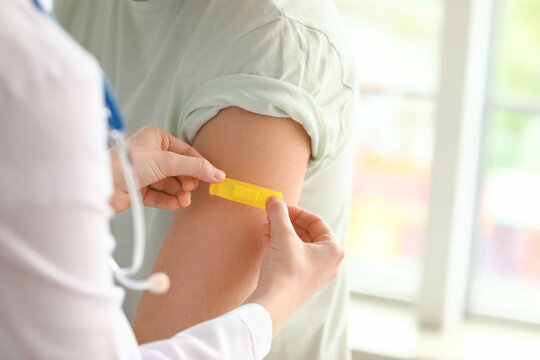 Doctor applying medical patch on patient's arm in clinic