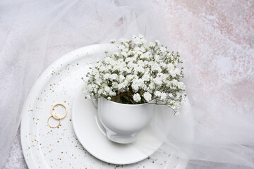 Composition with beautiful gypsophila flowers and wedding rings on light background