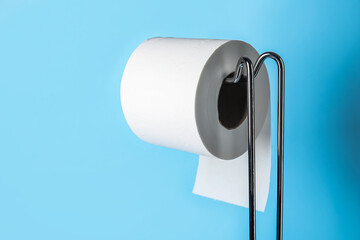 Modern holder with toilet paper roll on blue background, closeup