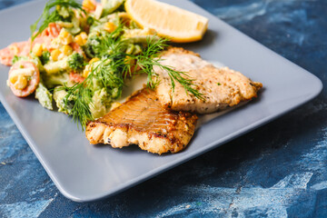 Plate with tasty baked cod fillet and vegetables on color background, closeup