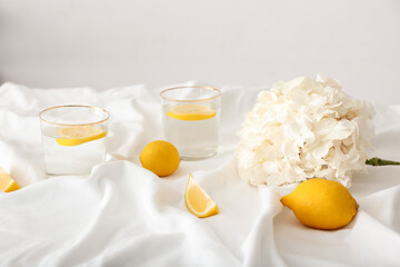 Hydrangea flower and glasses with lemon water on fabric background