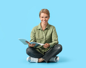 Young woman reading magazine on blue background