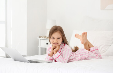 Obraz na płótnie Canvas Cute little girl watching cartoons on laptop in bedroom