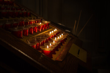 Red candle holdings with lighted up candles in a church.
