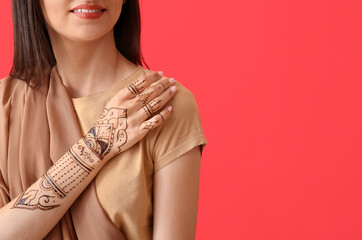 Beautiful Indian woman with henna tattoo on color background