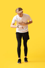 Fototapeta na wymiar Sporty male runner checking pulse on color background