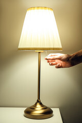 Woman turning off lamp in dark room