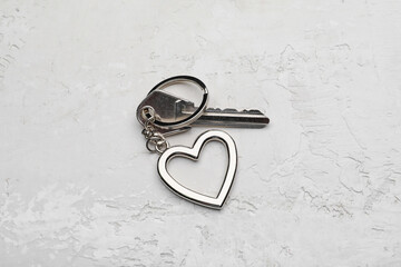 Key with heart shape keychain on light background