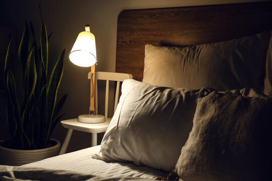 Glowing lamp on bedside chair in dark room