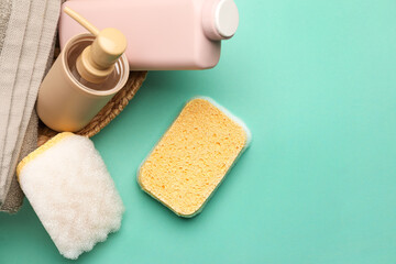 Bath sponges, bottles of cosmetic products and towel on color background