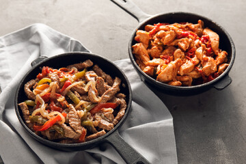 Frying pans with tasty Fajita on grey background