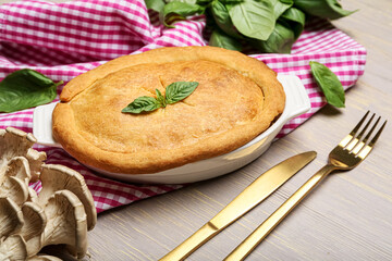 Baking dish with tasty mushroom pot pie on grey wooden background